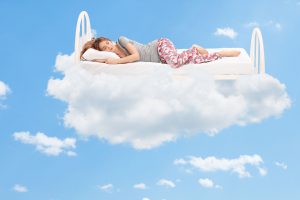 39577973 - relaxed young woman sleeping on a comfortable bed in the clouds