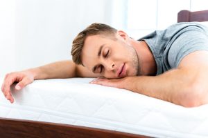 49654381 - photo of young man sleeping on nice white bed. young man demonstrating quality of mattress