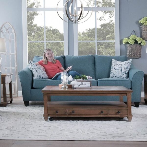 woman sitting on a blue couch with a wood coffee table in the front
